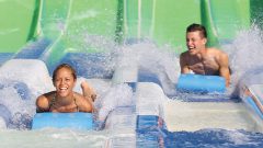 Two young adults spraying water at the bottom of Hydro Racer slide